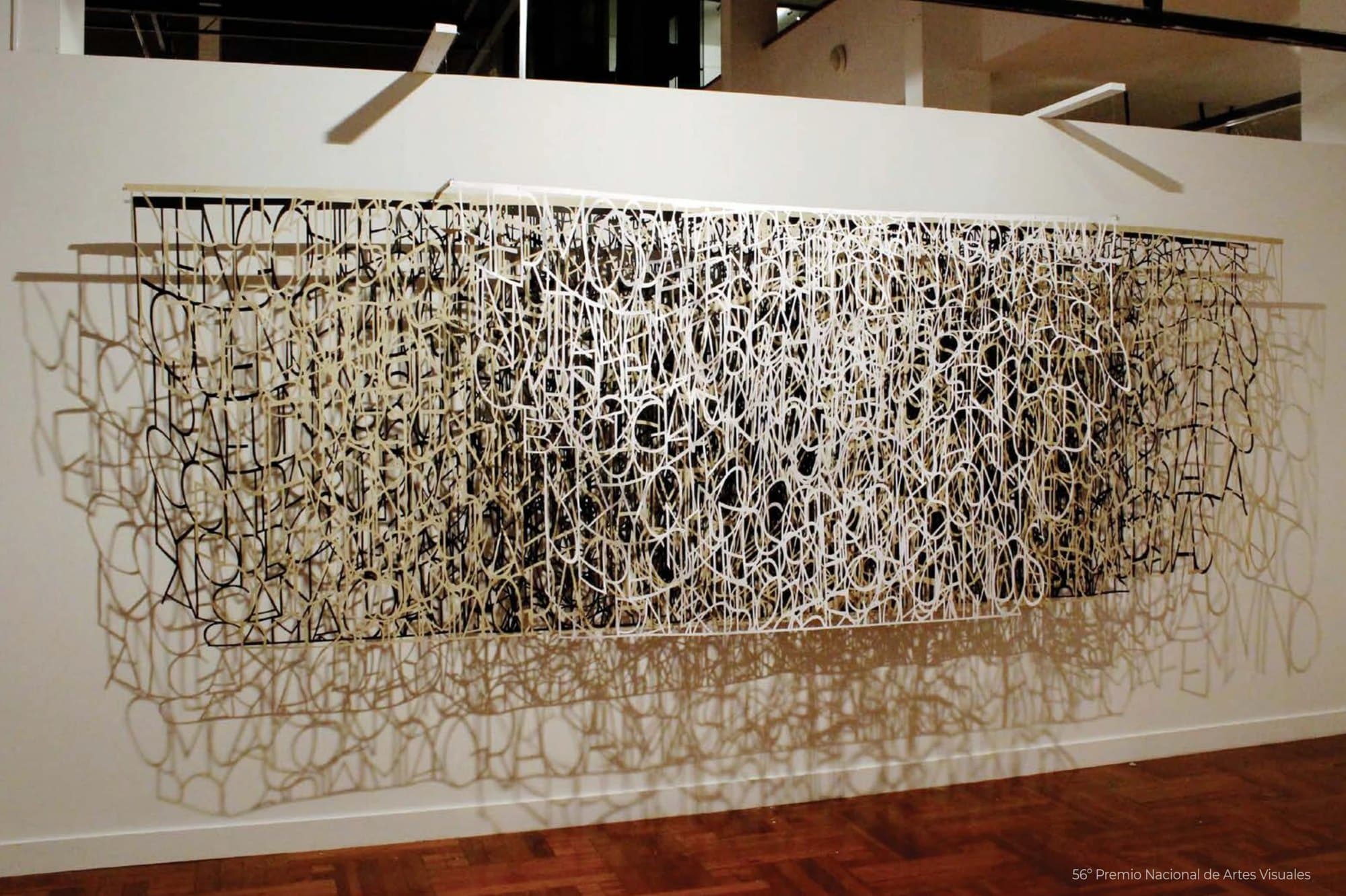 Palabras al vacío: capas de papel calado blanco, crudo y negro separadas del muro